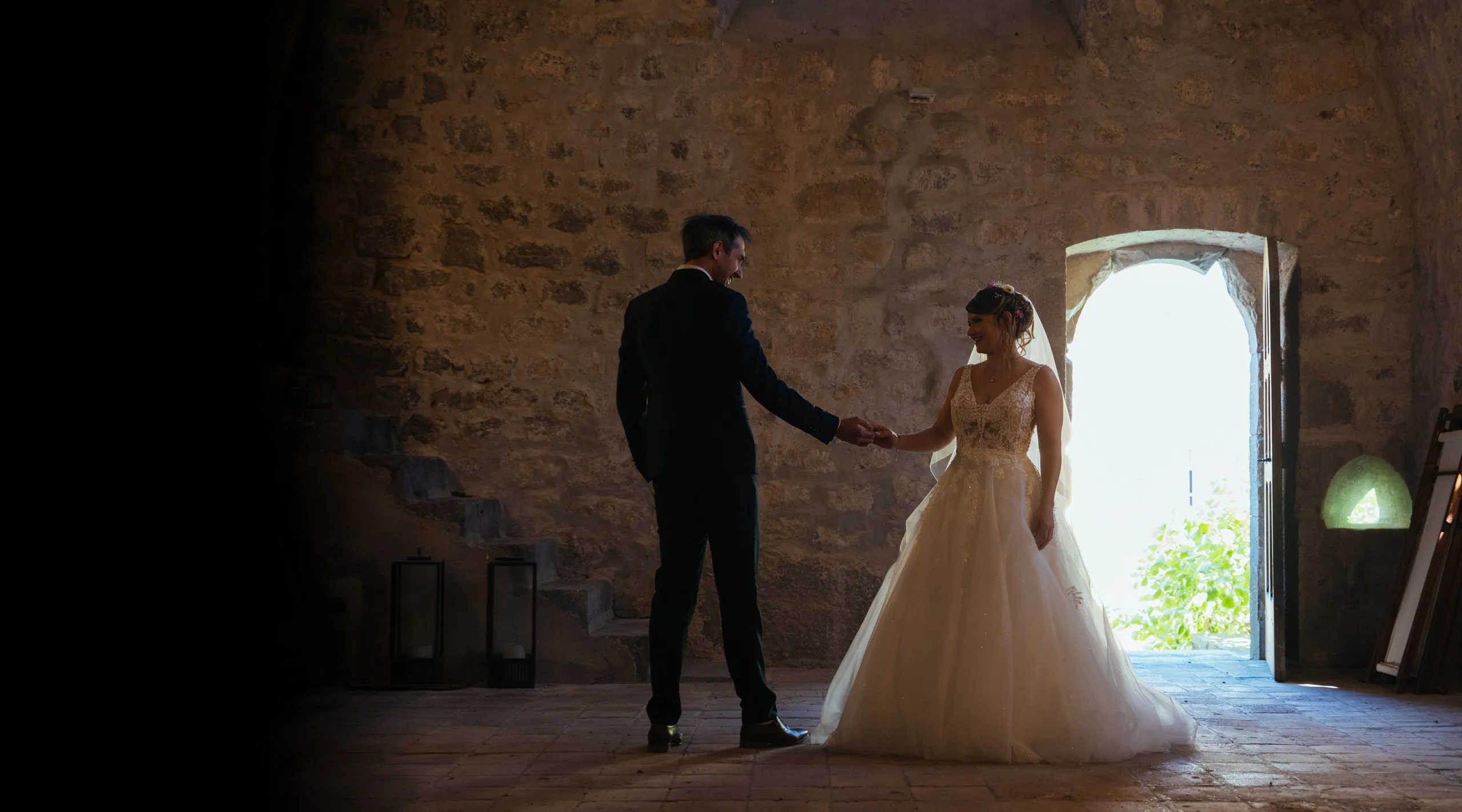 Photographe de mariage en Ardèche : les mariés se tiennent la main dans la salle en pierre du château de Saint-Alban-Auriolles, près de Ruoms